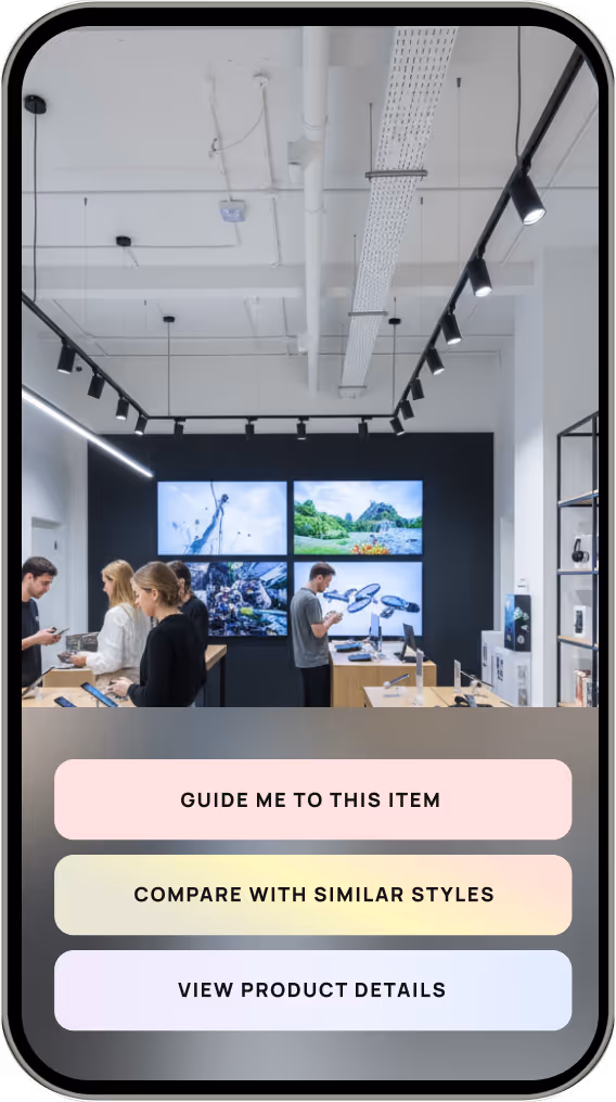 People browsing electronic devices inside a modern store with large screens on the back wall showing nature and tech images, overlaid with buttons: Guide Me to This Item, Compare With Similar Styles, View Product Details.