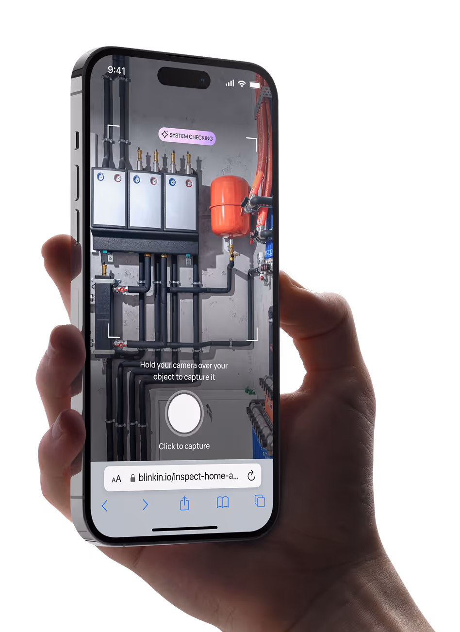 Hand holding smartphone displaying an app scanning a home heating system with pipes and a red expansion tank on the screen.